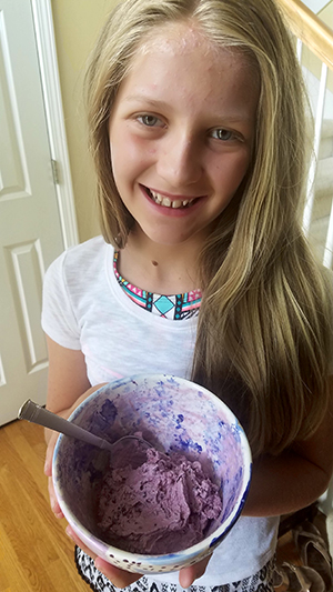 Camp participant holding her homemade blackberry ice cream that she made during the camp.