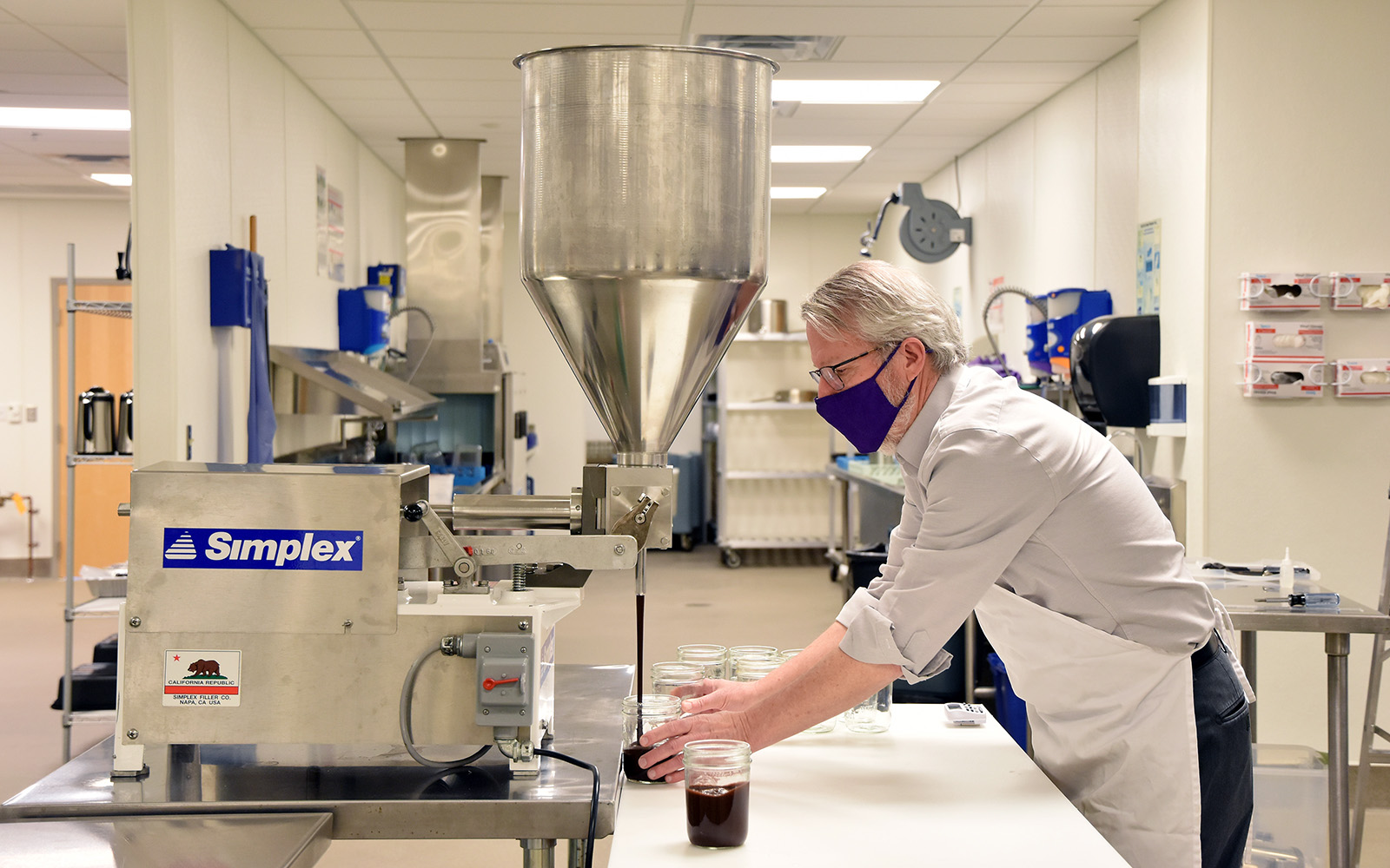 Bryan Severns using the Simplex filler to fill jars with chocolate sauce.