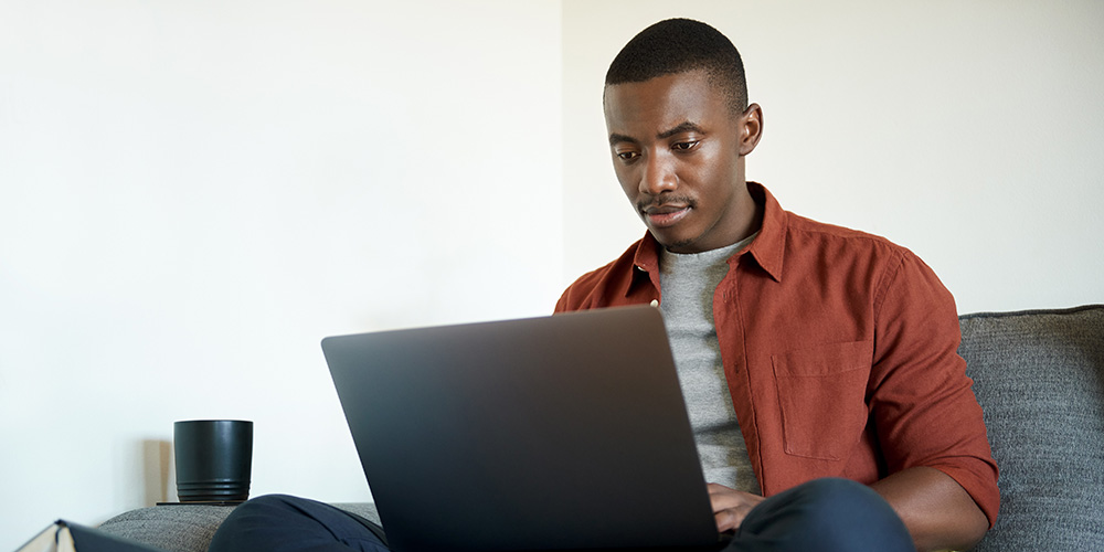 Man sitting on couch using a laptop.