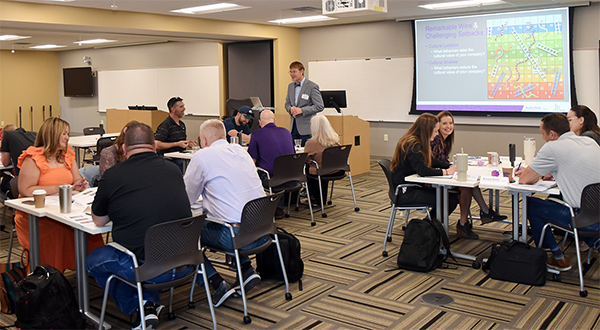 Instructor observing small groups' interactions at leadership workshop. 