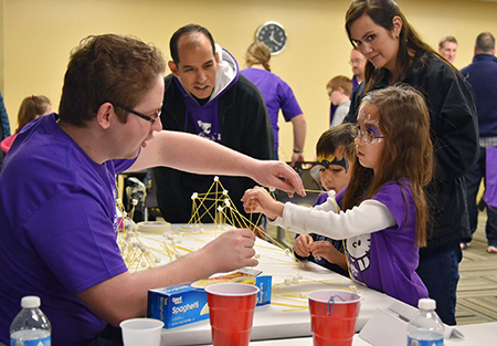 Family building structures with uncooked spaghetti noodles to learn about engineering.