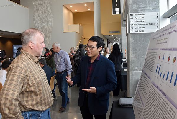 Two people talking next to a scientific poster in the Bistro at K-State Olathe.