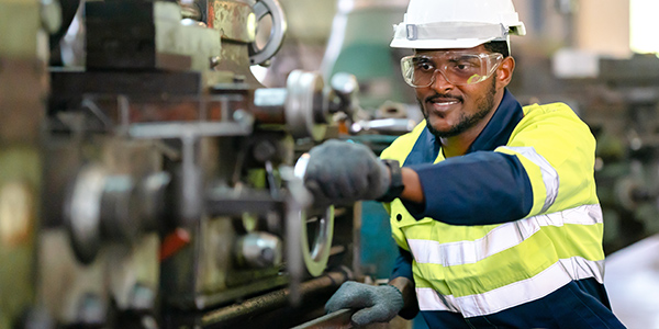 Engineer turning crank on a machine on the production floor. 