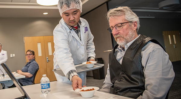 Student serving a participant a sample for a test.