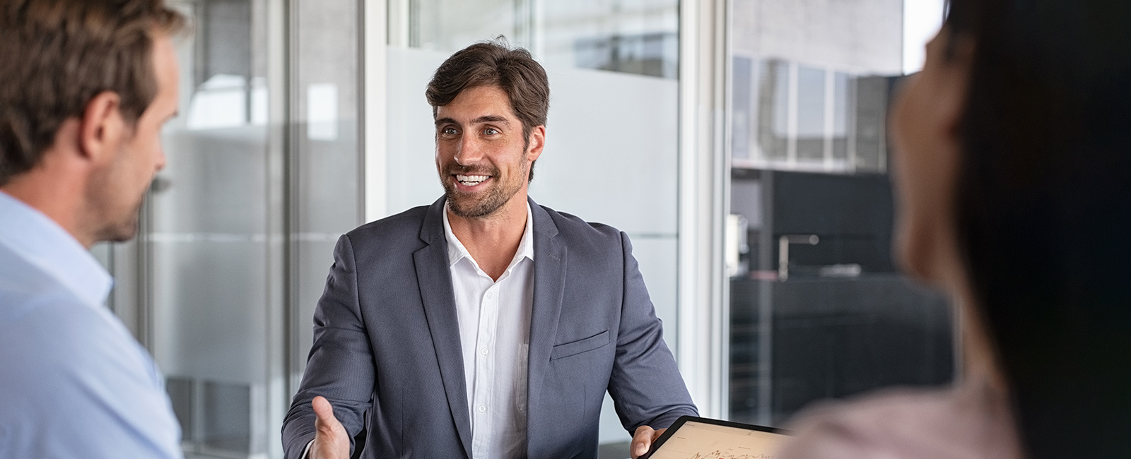 Man in suit discusses financial projections with clients.