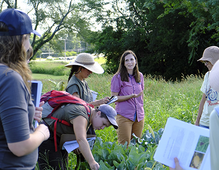 Local grower talking to students in a grassy field. 