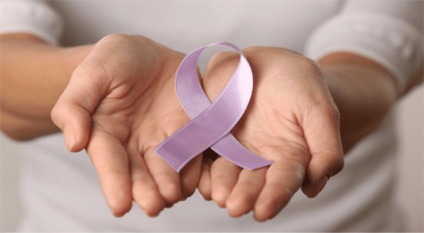Hands holding purple ribbon that signifies stomach cancer.
