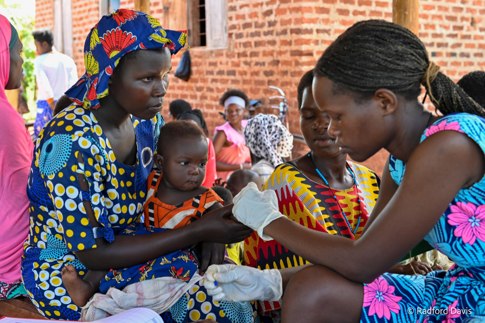 Ugandan mother holding her child during a clinical examination.